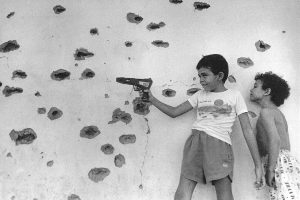 1-	En una zona frecuente de enfrentamientos entre la guerrilla y el ejército salvadoreño, niños juegan con un arma de juguete a la guerra, simulando los hechos vividos en su lugar de origen. Chalatenango, 1992. (Luis Galdámez/Espacio Revista)